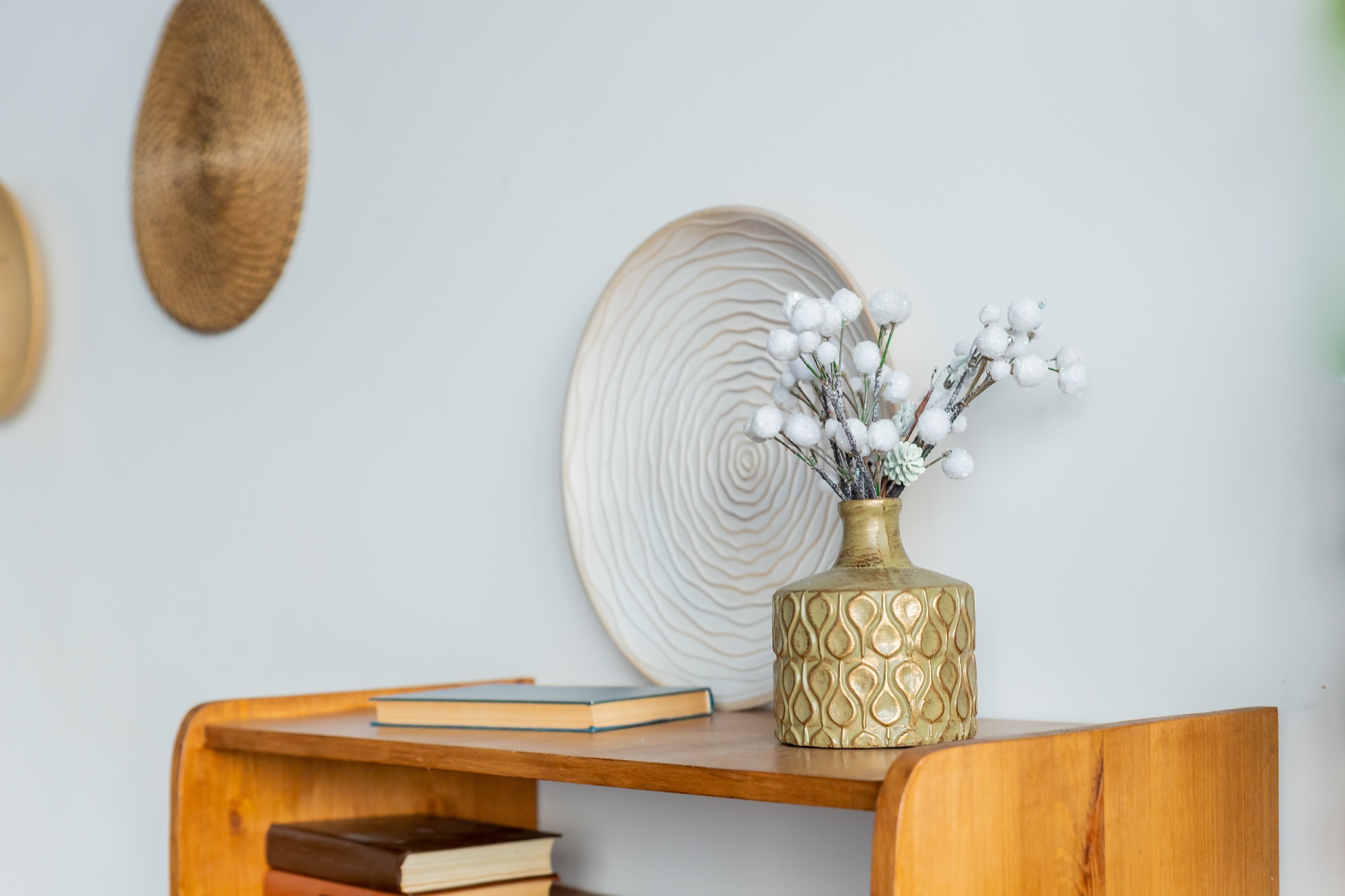 Home interior. Gold vase with dry branches is syanding on a small table. decorative elements
